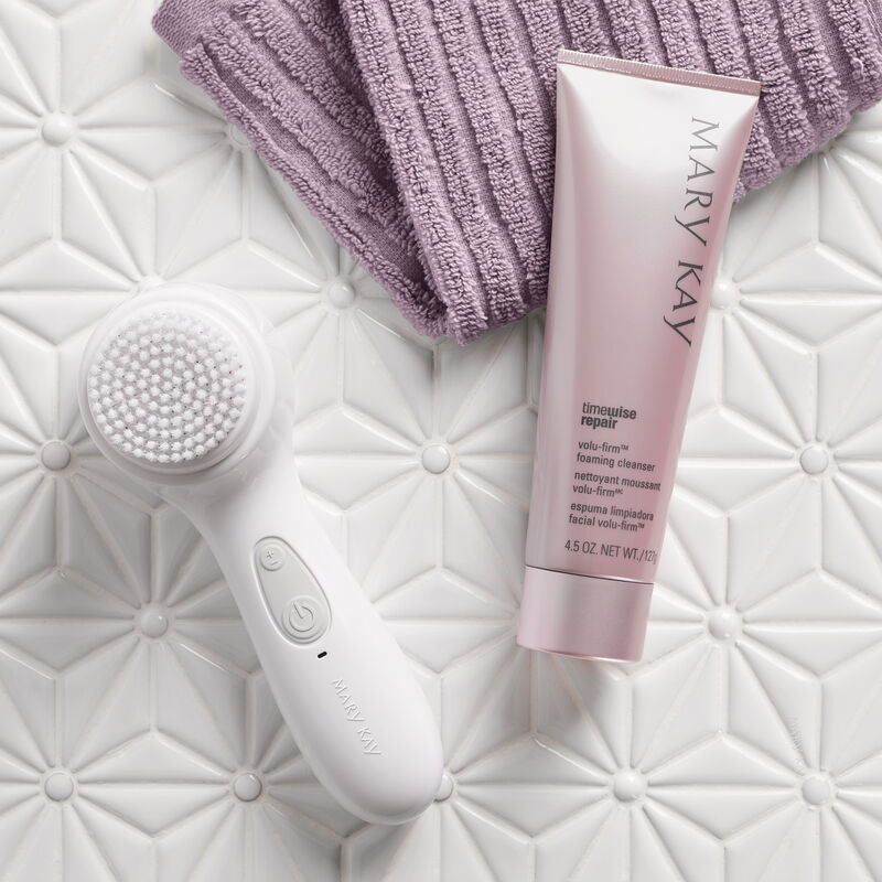 A tube of Mary Kay TimeWise Repair Volu-Firm Foaming Cleanser with Skinvigorate Sonic Skin Care System in a bathroom setting.