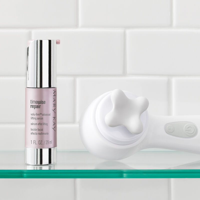 A bottle of Mary Kay TimeWise Repair Volu-Firm Advanced Lifting Serum with Skinvigorate Sonic Skin Care System in a bathroom setting.